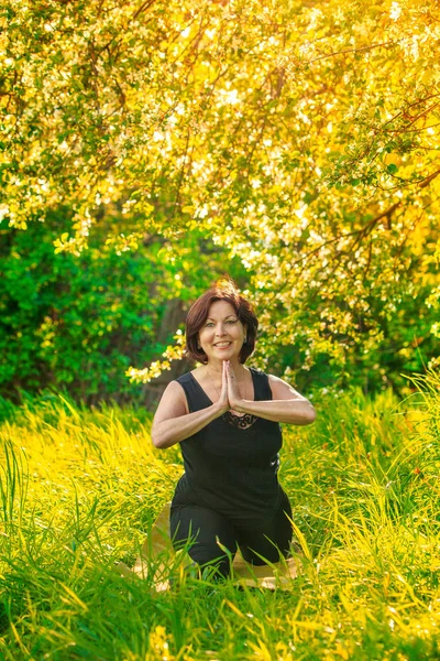 Mooie vrouw doet yoga buiten op gras — Stockfoto