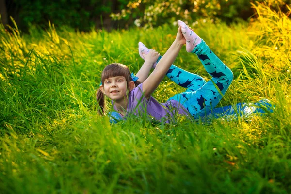 Piękna dziewczyna robi joga na zewnątrz na zielonej trawie — Zdjęcie stockowe