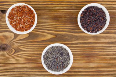 Ahşap arka plan üzerinde kapta çiğ mavi pirinç 