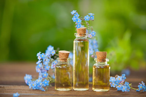 Esencia de flores en la mesa en un hermoso frasco de vidrio —  Fotos de Stock