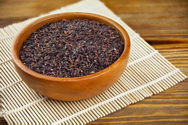 Ahşap arka plan üzerinde kapta çiğ siyah pirinç 