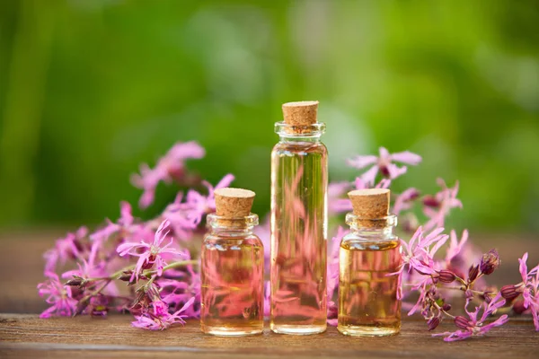 Esencia de flores en la mesa en un hermoso frasco de vidrio — Foto de Stock