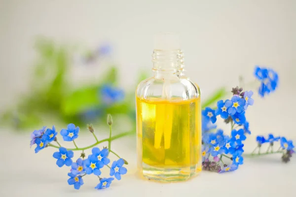 Esencia de flores en la mesa en un hermoso frasco de vidrio — Foto de Stock