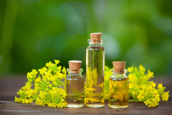 Esencia de flores en la mesa en un hermoso frasco de vidrio — Foto de Stock