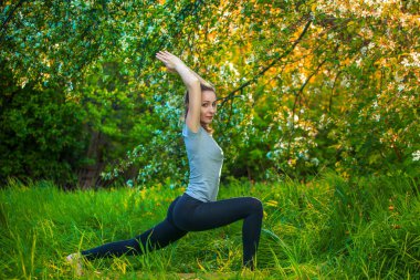 güzel kadın açık havada yeşil çimenlerin üzerinde yoga yaparken