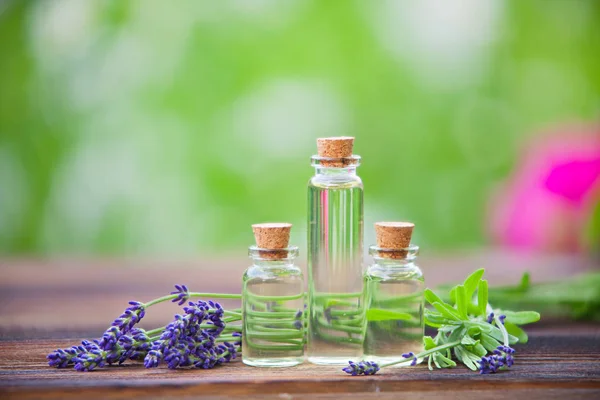 Esencia de flores de lavanda en la mesa en un hermoso frasco de vidrio — Foto de Stock