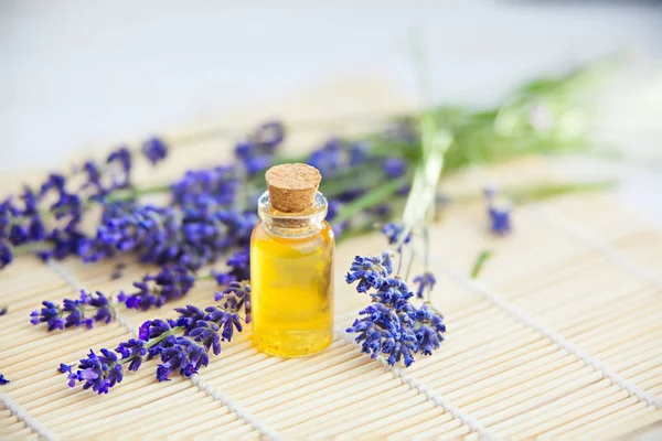 Esencia de flores de lavanda en la mesa en un hermoso frasco de vidrio — Foto de Stock