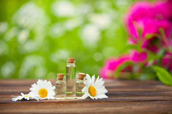 Essence of flowers on table in beautiful glass jar — Stock Photo, Image