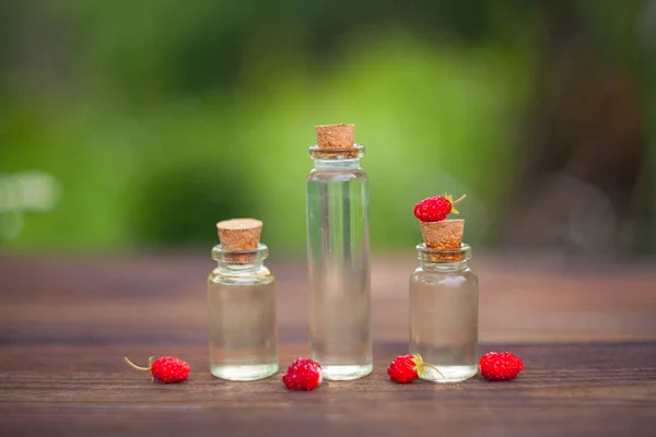 Esencia de fresa silvestre en la mesa en una hermosa botella de vidrio — Foto de Stock