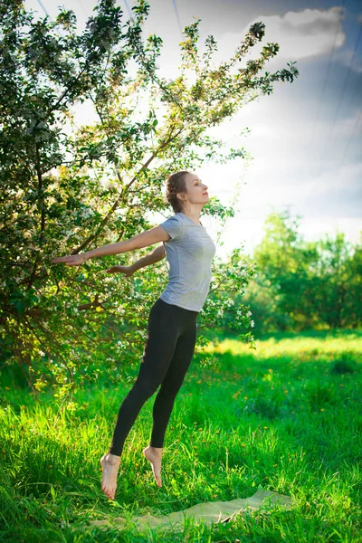 Bela mulher fazendo ioga ao ar livre na grama verde — Fotografia de Stock