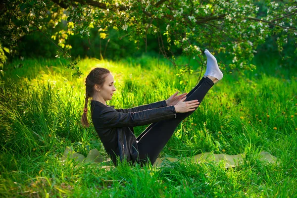 Kobieta robi joga na zewnątrz na zielonej trawie — Zdjęcie stockowe