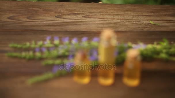 Ефірна олія на столі в красивій пляшці з квітами — стокове відео