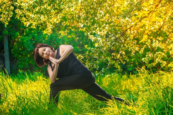 Красивая женщина, занимающаяся йогой на открытом воздухе на зеленой траве — стоковое фото