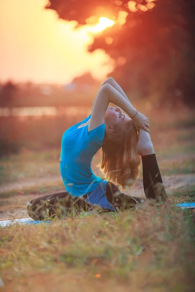 Piękna kobieta robi joga na zewnątrz na zielonej trawie — Zdjęcie stockowe