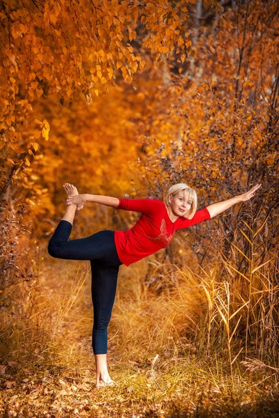 Bella donna che fa yoga all'aperto su foglie gialle — Foto Stock