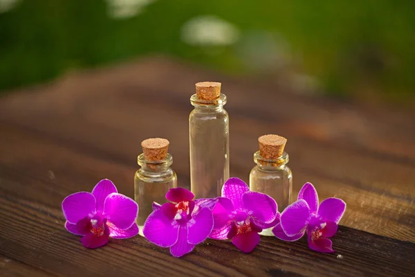 Essentie van orchideebloemen op tafel in mooie glazen pot — Stockfoto