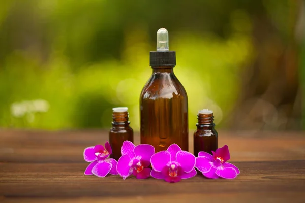 Esencia de flores de orquídea en la mesa en un hermoso frasco de vidrio — Foto de Stock