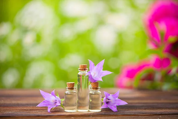 Esencia de flores en la mesa en un hermoso frasco de vidrio — Foto de Stock