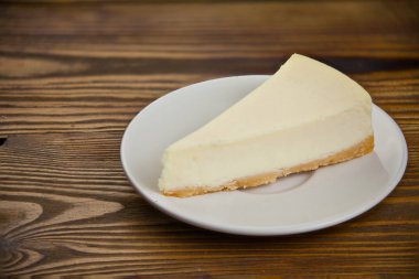 ahşap masa üzerinde beyaz tabakta klasik cheesecake