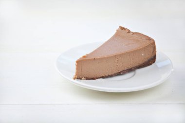 ahşap masa üzerinde beyaz tabakta çikolatalı cheesecake