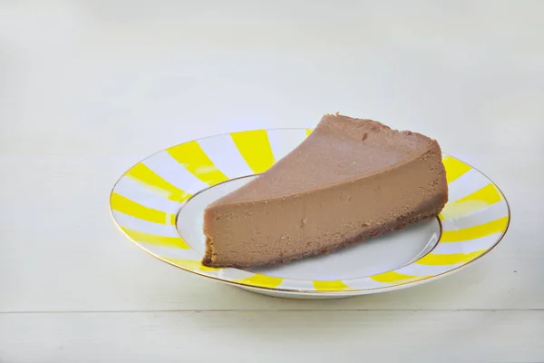 Pastel de queso de chocolate en plato blanco en mesa de madera — Foto de Stock
