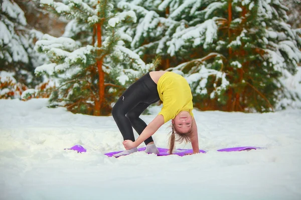 beautiful woman doing yoga outdoors in the snow