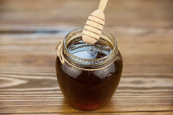 Deliciosa y deliciosa miel en frasco sobre la mesa — Foto de Stock