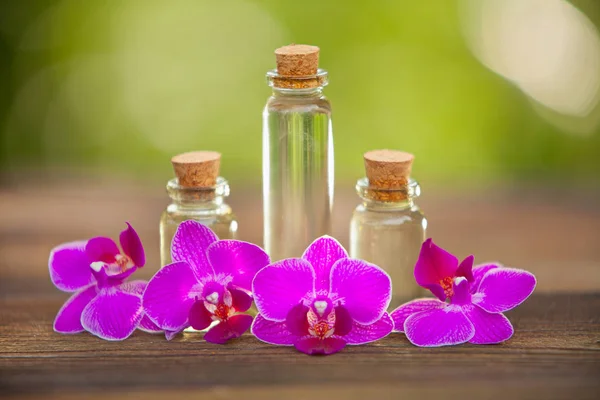Essentie van orchideebloemen op tafel in mooie glazen pot — Stockfoto
