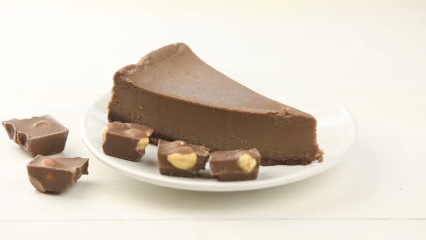 Шоколадный чизкейк на белой тарелке на деревянном столе — стоковое видео