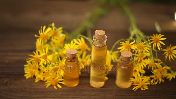 Ätherisches Öl auf dem Tisch in einer schönen Flasche mit Blumen — Stockvideo