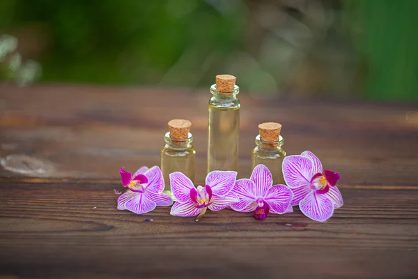 Esencia de flores de orquídea en la mesa en un hermoso frasco de vidrio — Foto de Stock