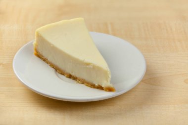 ahşap masa üzerinde beyaz tabakta klasik cheesecake