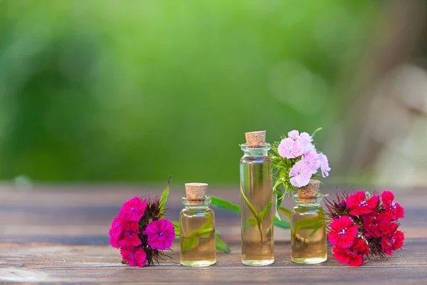 Essence of flowers on table in beautiful glass jar — Stock Photo, Image