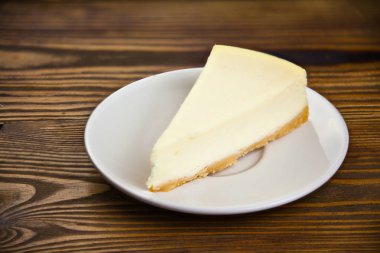 ahşap masa üzerinde beyaz tabakta klasik cheesecake