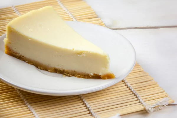 白いテーブルに白いプレートに古典的なチーズケーキ — ストック写真