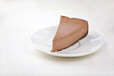 ahşap masa üzerinde beyaz tabakta çikolatalı cheesecake