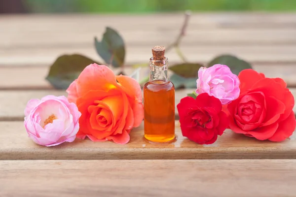 Esencia de rosa en la mesa en una hermosa botella de vidrio — Foto de Stock