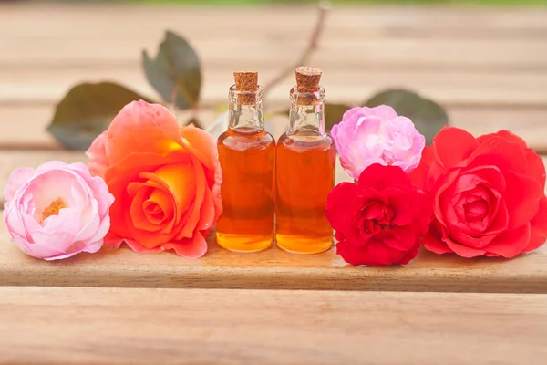 Esencia de rosa en la mesa en una hermosa botella de vidrio — Foto de Stock