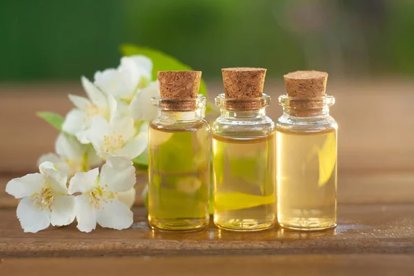 Essence of flowers on wooden background in beautiful glass jar — Stock Photo, Image