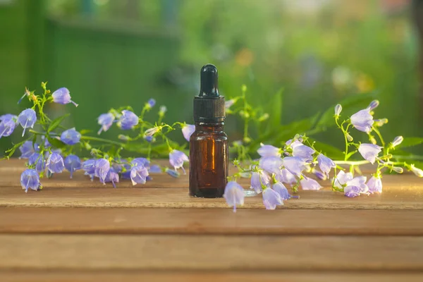 Esencia de flores en la mesa en un hermoso frasco de vidrio — Foto de Stock