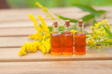 goldenrod essential oil in  beautiful bottle on table clipart