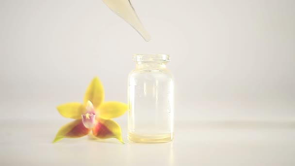 美しいガラスの瓶にテーブルの上の蘭の花の本質 — ストック動画
