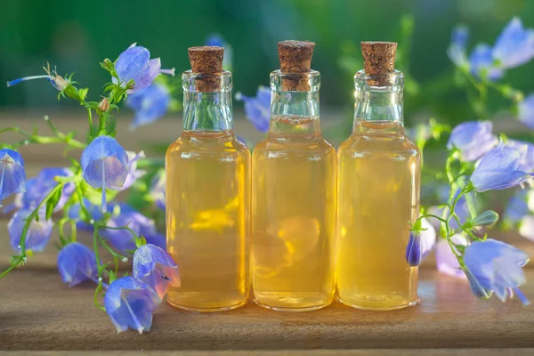 Esencia de flores en la mesa en un hermoso frasco de vidrio — Foto de Stock