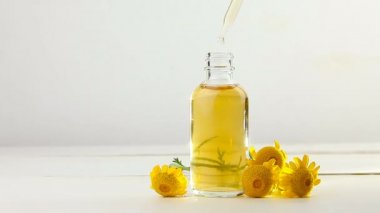 Sarı Camomille çiçeklerinin esansı beyaz arka planda güzel cam şişe