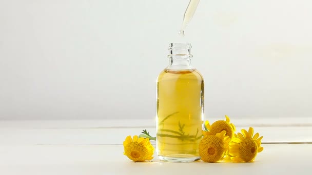 美丽玻璃瓶中白色背景下黄色卡莫美花的精华 — 图库视频影像