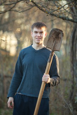 Ziraat Mühendisi güçlü yakışıklı çiçek yatak arka plan üzerinde kürek ile