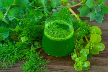 Ahşap kahverengi masada yeşil otlu smoothie.