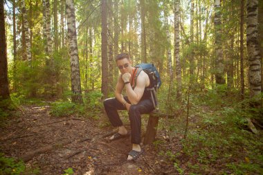 Bahar ormanında bir bankta dinlenen yakışıklı adam.