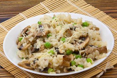 Tahta arka planda beyaz bir tabakta leziz bir risotto.