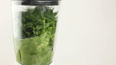Beyaz arkaplanda bir blender içinde yeşil bir smoothie hazırlamak